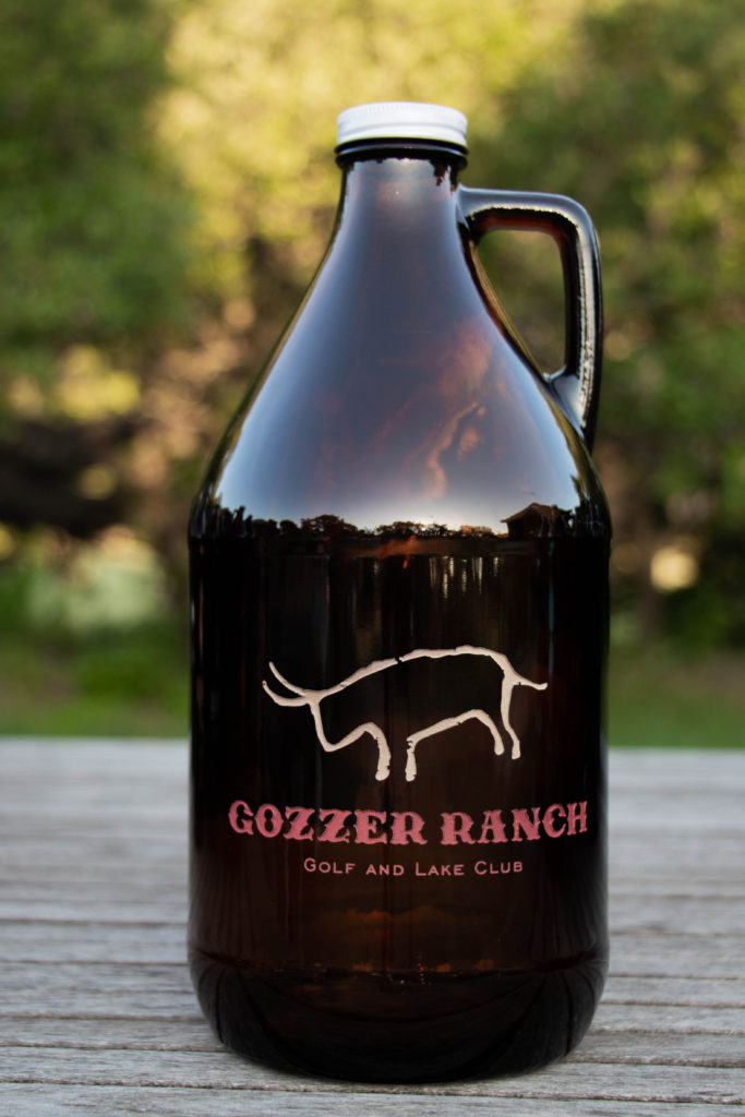 Sandcarved and painted growler with Discovery Land Co Gozzer Ranch logo